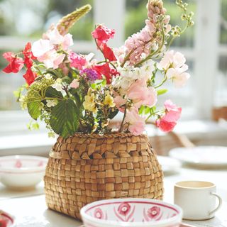 A set table with a vase of flowers in a wicker basket