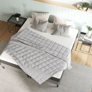White bed in bedroom with grey weighted blanket