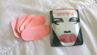 A package of Hostage Mouth Tape open on a bed with the mouth tape next to it