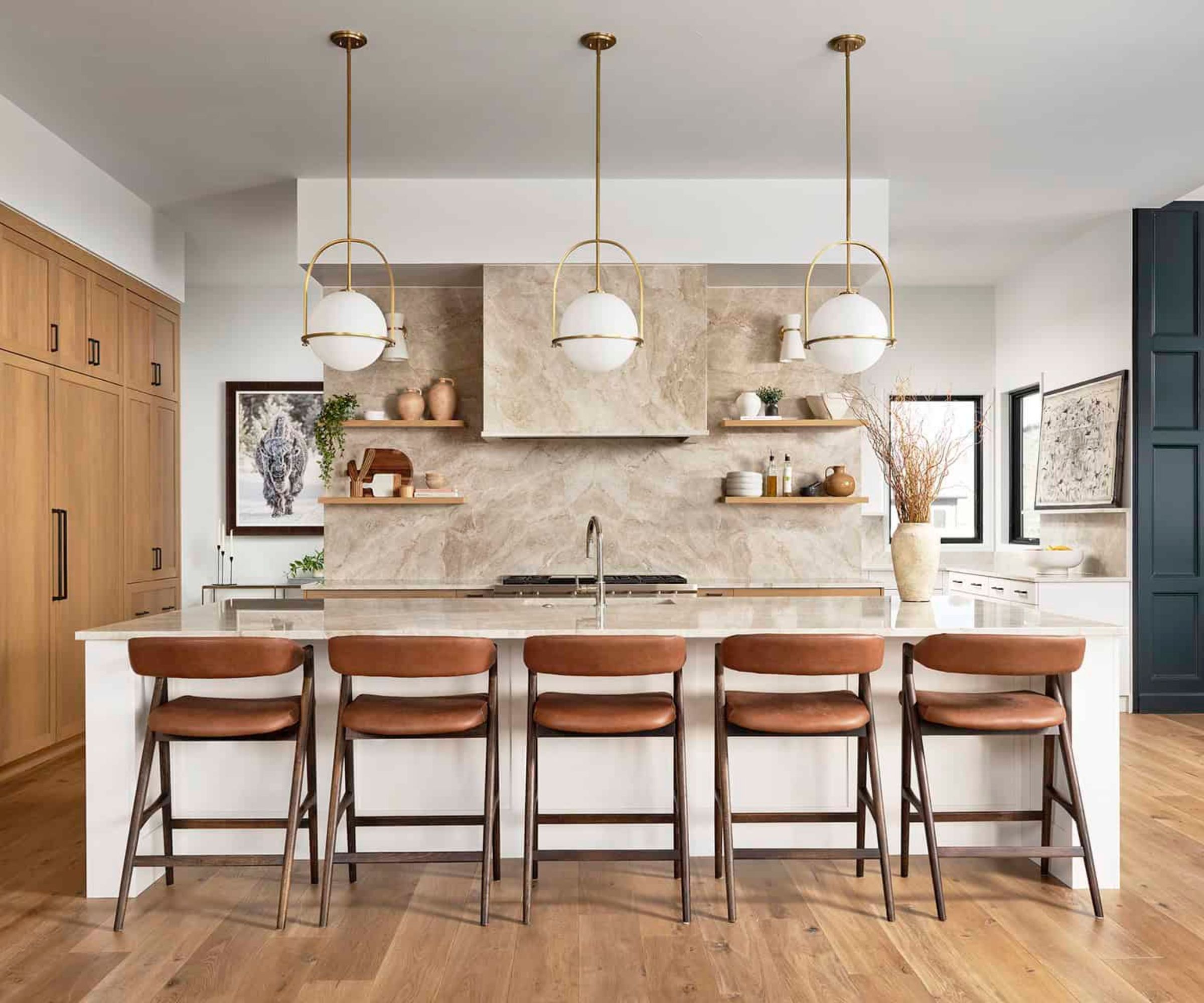 A large kitchen with full length wood cabinets, a white island, and a mix of brass, silver, and black hardware