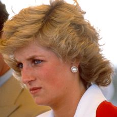 Princess Diana scowling wearing a red and white dress