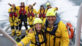 Wynne and Joanna on a boat with the RNLI crew all in yellow waterproofs