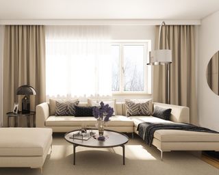 A modern living room with cream sofa, mushroom lamp, round mirror, dressed with beige drapes and sheer voile curtains