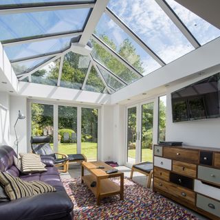 white conservatory with sofa and walled tv