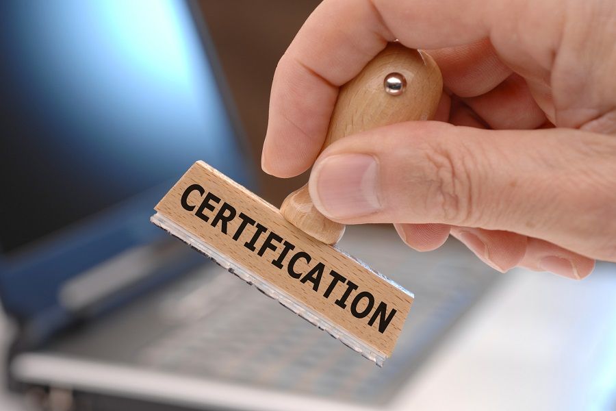 Hand holding a wooden ink stamp stating &amp;#039;certification&amp;#039;.