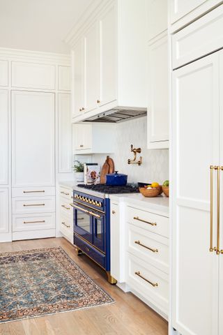 white kitchen with wooden floor with rug in front of navy range cooker