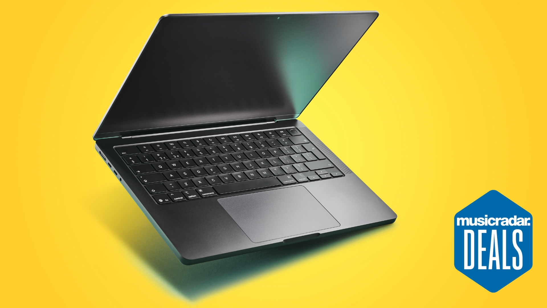 A MacBook Pro M5 laptop on a yellow background with the MusicRadar deals logo