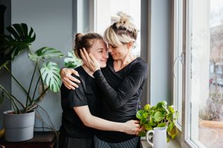 A woman hugging her teenage daughter