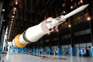a large white rocket on display, in horizontal configuration, in a museum