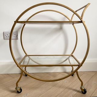 golden frame bar cart with white wall and wooden flooring