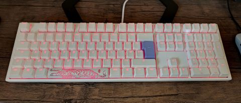 A white Ducky One 3 mechanical keyboard on a wooden desk.