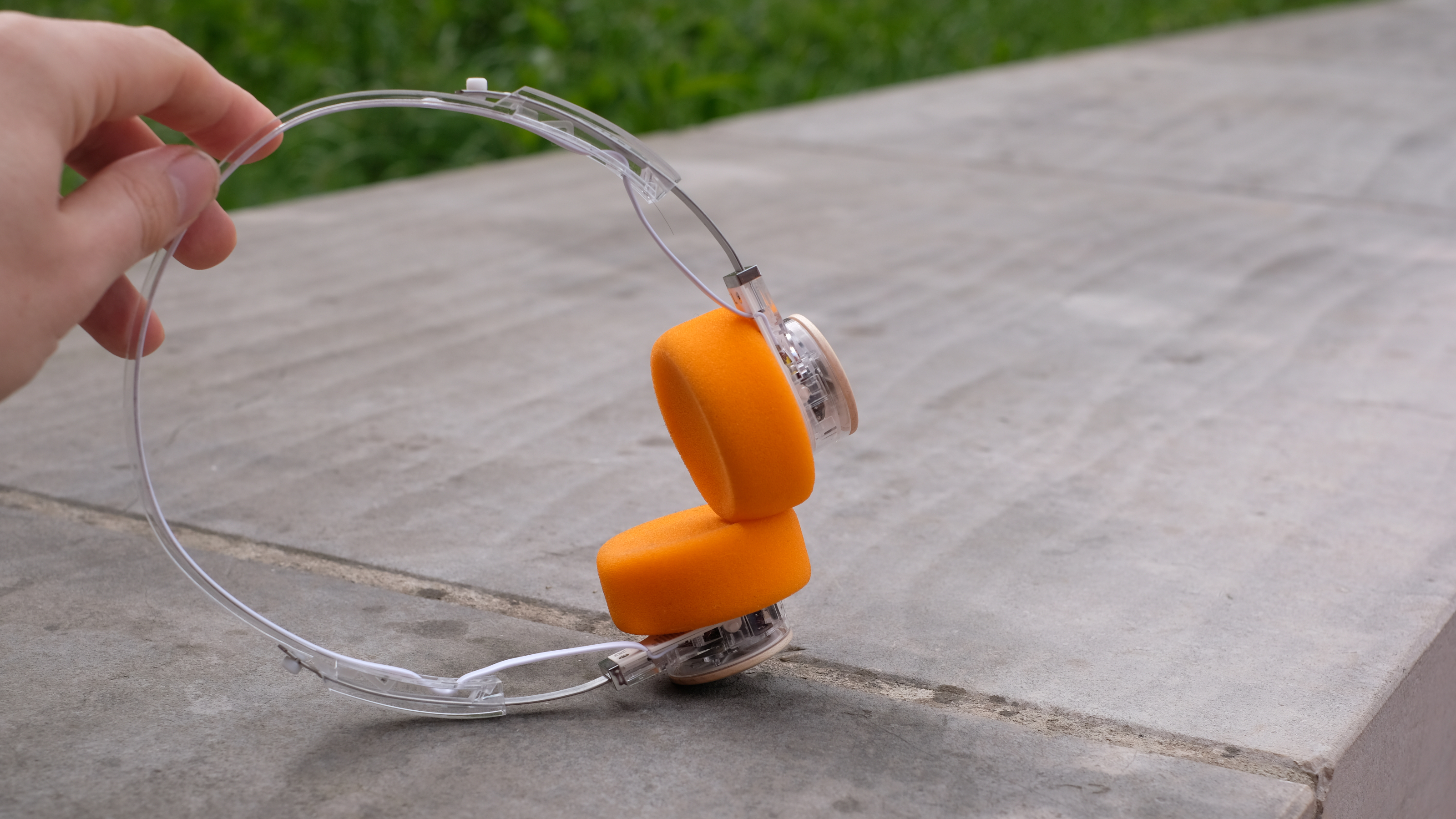 A photograph of the FiiO EH11 over-ear headphones with a transparent frame and orange foam earpads.