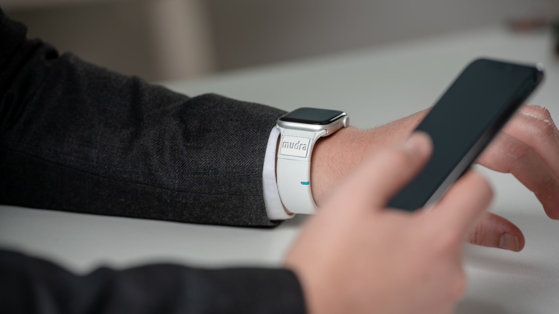 Une personne utilise un bracelet Apple Watch Mudra Band pour contrôler son iPhone.
