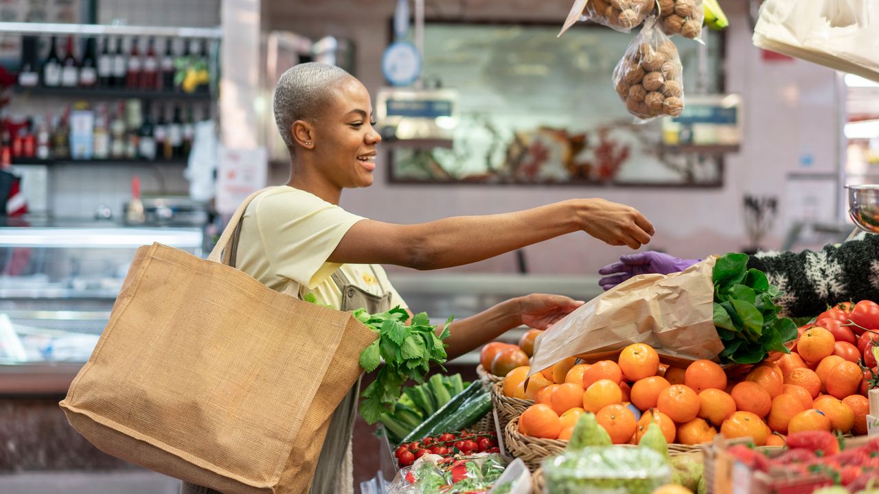 Women picks up produce from a fruit and vegetable aisle in the supermarket