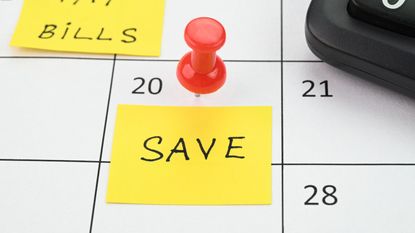 'Save' written on a yellow note stuck to a calendar with a red pin 
