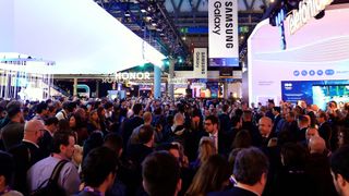 A low shot of the crowd at Mobile World Congress, on the show floor with large banners from companies such as Telefonica, Samsung, and HONOR on display.