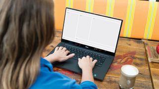 A woman sits at a laptop tweaking a CSS Grid layout