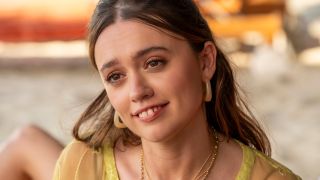 Aimee Lou Wood tilts her head slightly as she smiles on a beach in The White Lotus S3 E8 - "Amor Fati."