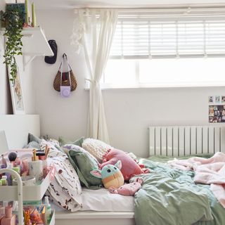 White room with bed cushions and plush toys, window