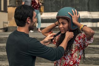 (L to R) Eugenio Mastrandrea as Lino Ortolano and Zoe Saldana as Amy Wheeler putting on a helmet with the help of Lino