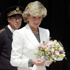Princess diana wearing a white blazer holding flowers
