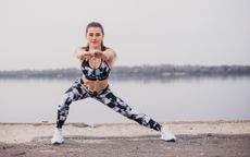 A woman performing a lateral lunge outdoors as part of a lower-body workout 