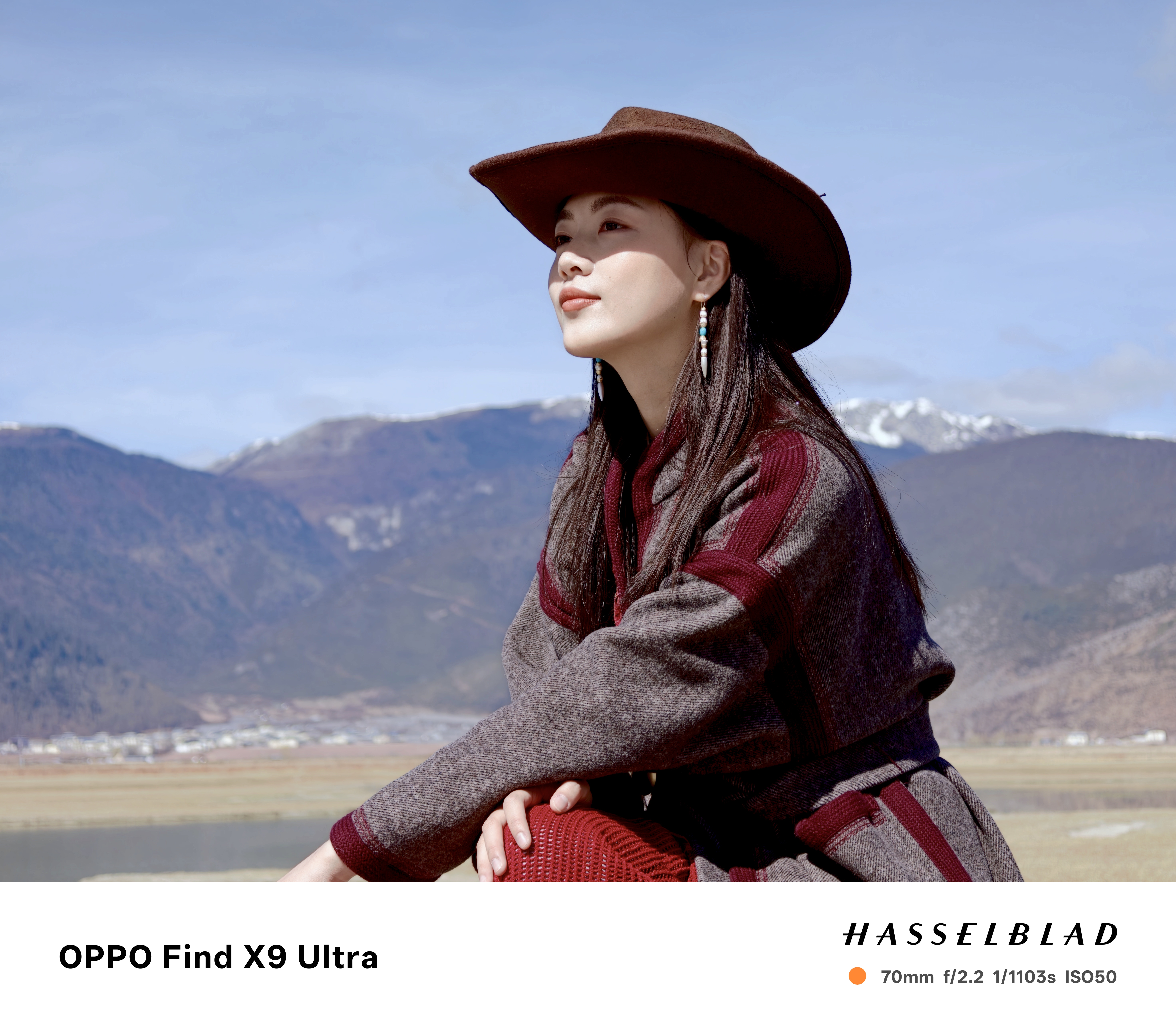 Chinese woman in a cowboy hat posing for a photo with a snoy mountain backdrop