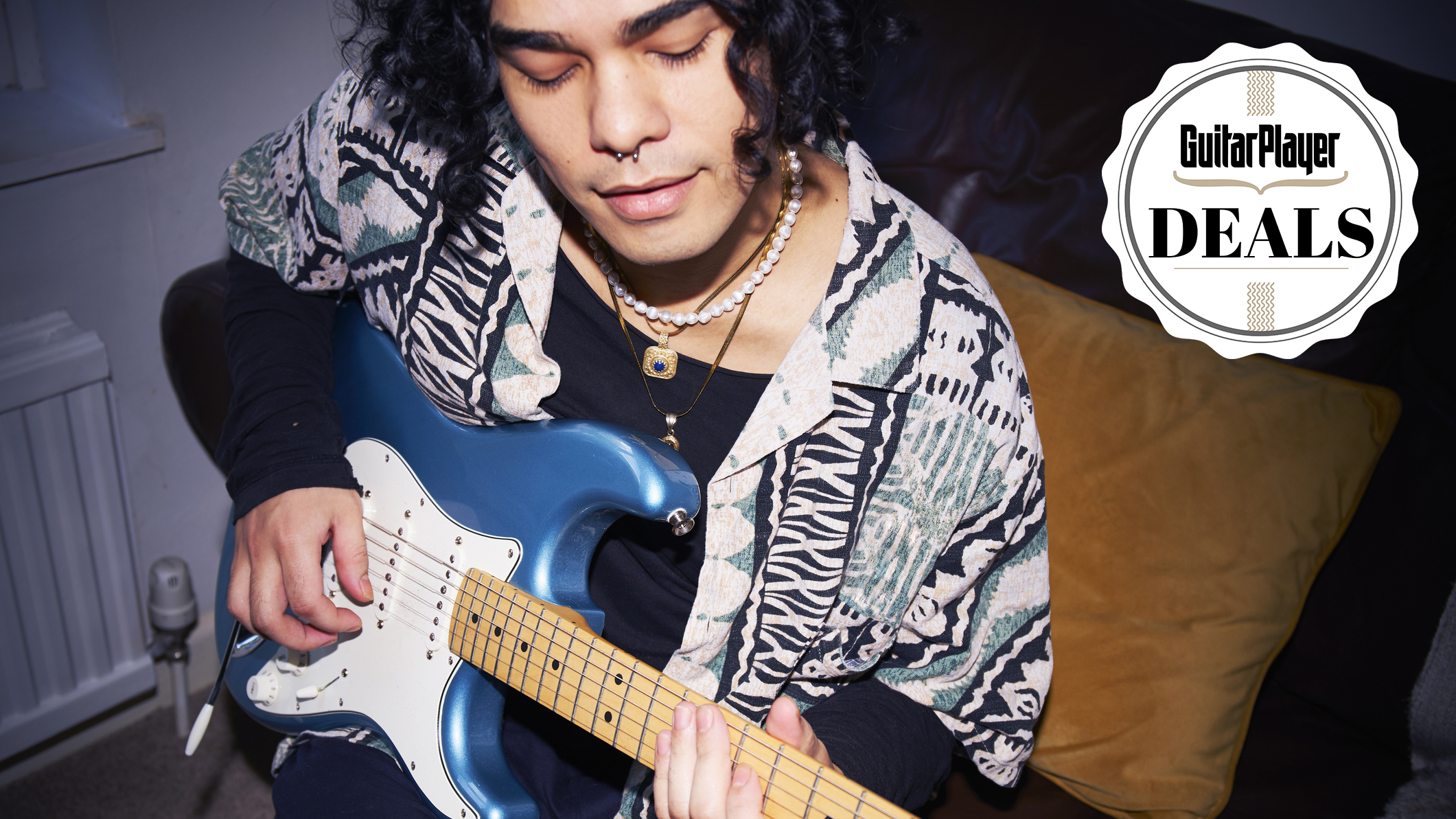 Man with long hair playing a blue Stratocaster