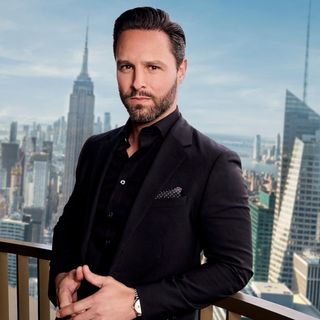 Justin Tuinstra wearing a black suit on a rooftop in a promo shot of Selling the City S1.