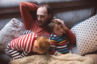 A dad and two young children lying on a sofa