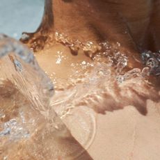 A woman with water splashing onto her collarbone