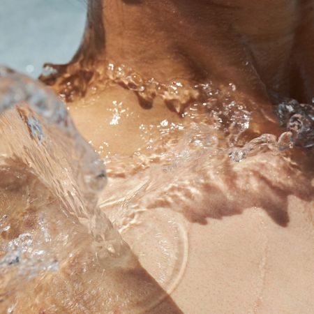 A woman with water splashing onto her collarbone