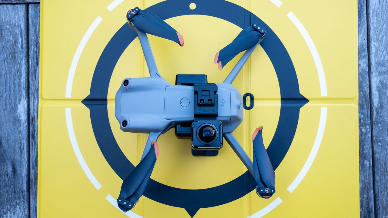 A DJI drone on a wooden table connected to the Insta360 Sphere 360 camera