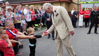 Prince Charles, Prince of Wales greets a child during his visit to Morecambe fire station