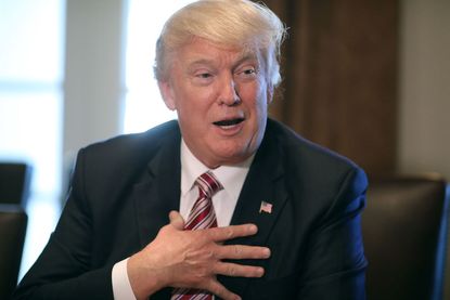 President Trump rests his hand on his chest in a "who, me?" expression.
