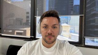 TechRadar writer Max Langridge wearing a white pair of the Sonos Ace headphones.