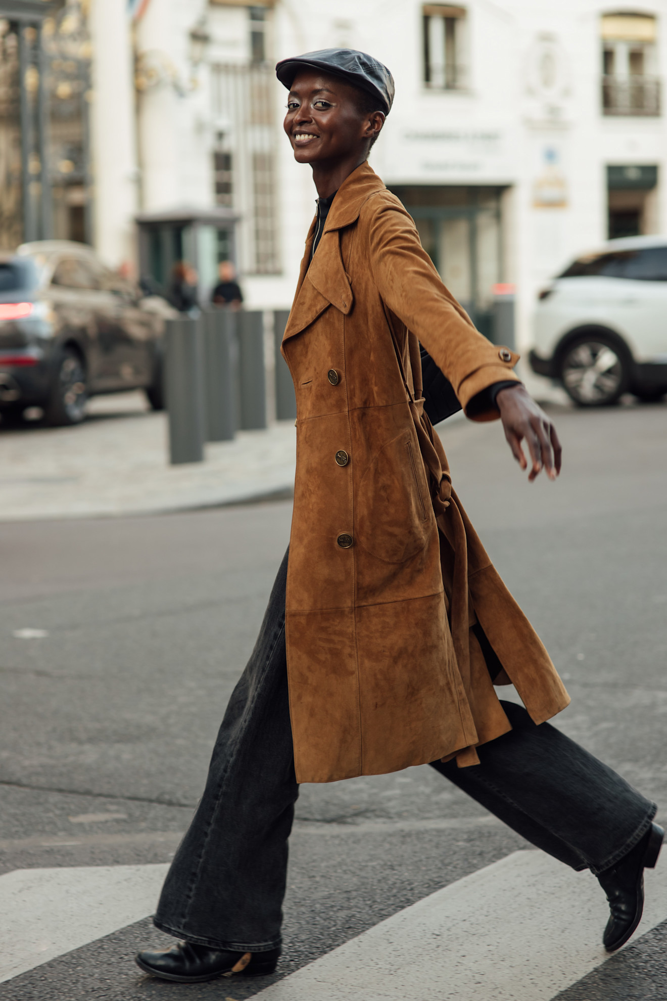 Person in black wide-leg jeans, black cowboy boots, and a corduroy long jacket.