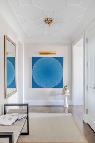 a large white hallway with blue art and a crystal light fixture