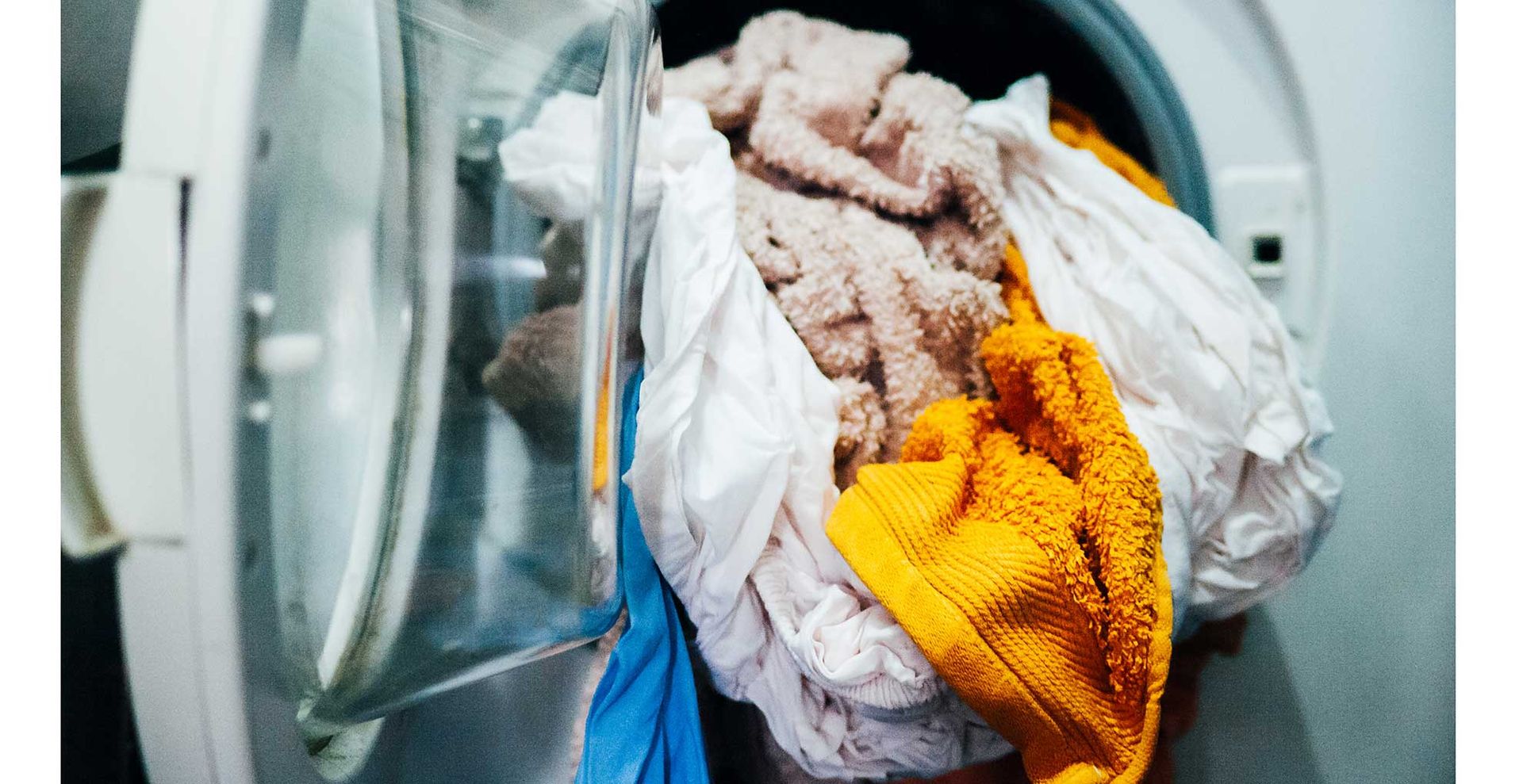 washing machine open with coloured bath towels with bed sheets in the same wash