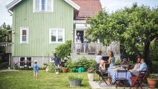 A house in the summer with a family playing outside. 