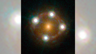 A bright, orange circle in the center of a ring of light. Four bright white spots form a cross shape on the circle's perimeter