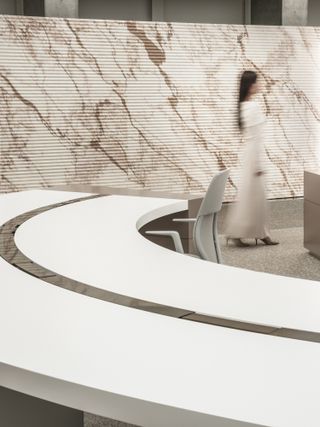 A circular desk and beige marble wall