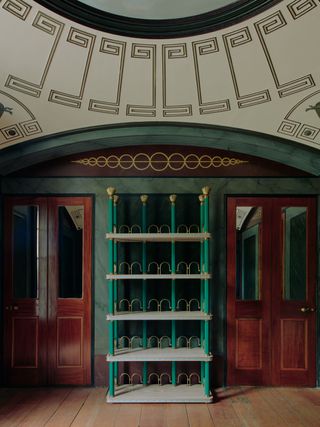 One of the collection’s centrepieces is the Hambledon Bookcase, made of limed solid oak shelves with grosgrain ribbon banding, green lacquer octagonal columns and aged solid brass fretwork and cast finials