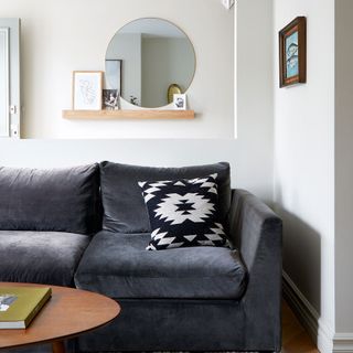 White living room with charcoal sofa in front of shelf with mirror