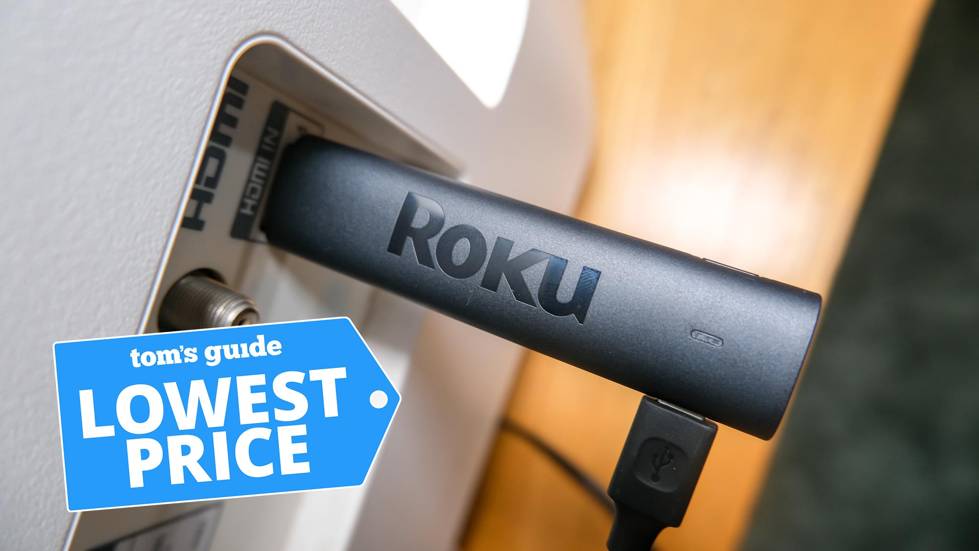 The Roku Streaming Stick 4K plugged into an HDMI port, with a Tom's Guide Lowest Price graphic above