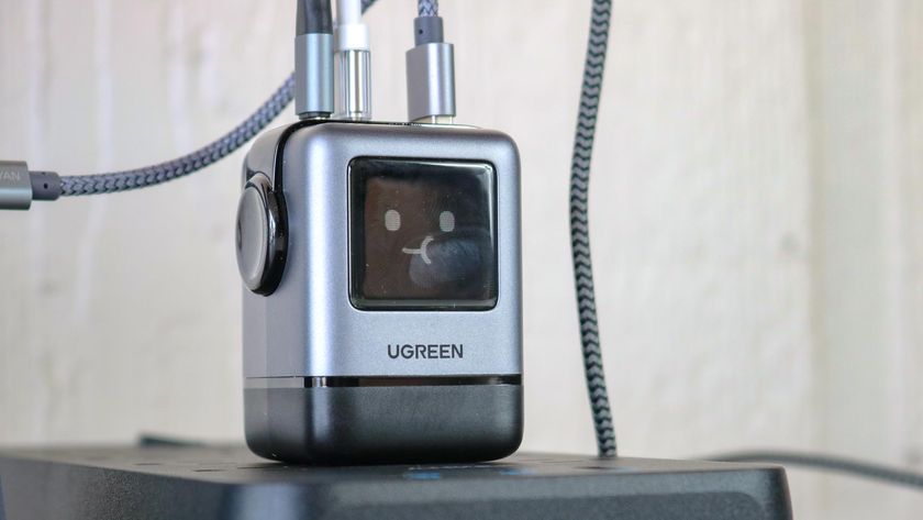 The Ugreen Uno Charger 100W plugged into a surge protector on a table with multiple cables connected