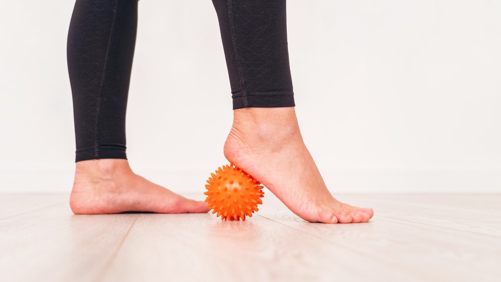 a photo of a woman rolling a ball under her foot