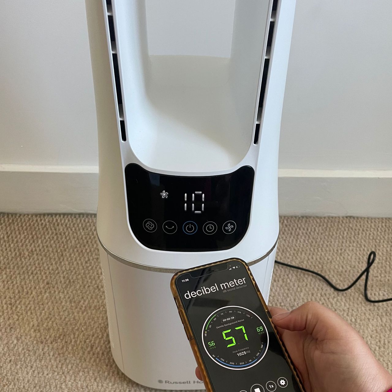 Hand holding a phone with a decibel meter in front of the Russell Hobbs RHBLDL12 Bladeless Tower Fan