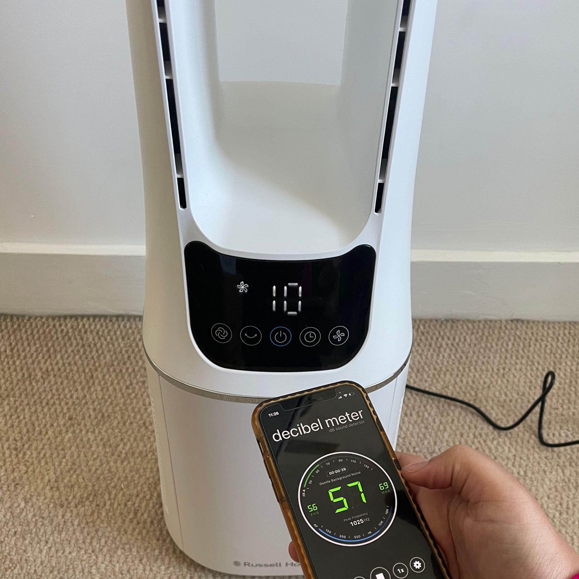 Hand holding a phone with a decibel meter in front of the Russell Hobbs RHBLDL12 Bladeless Tower Fan