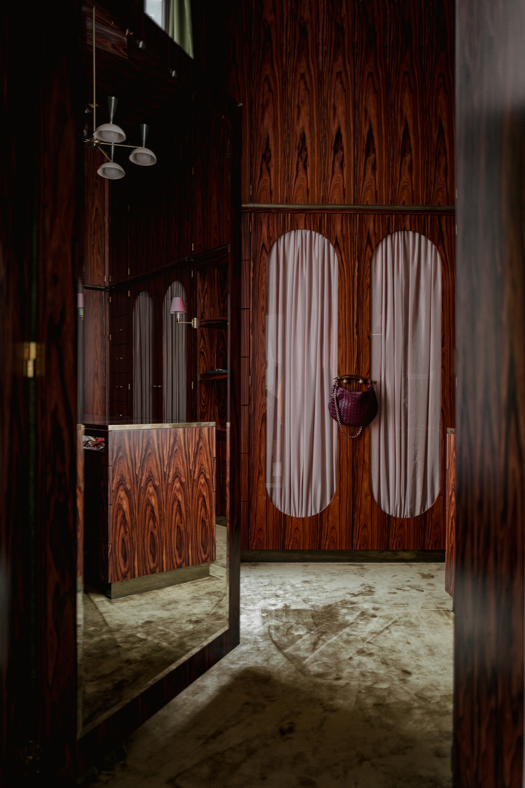 a timber closet with pill shaped cut outs and curtains inside with carpeted floors